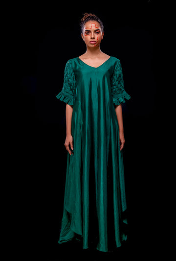 Front view of a green asymmetrical gown with pintuck basket weave sleeve.