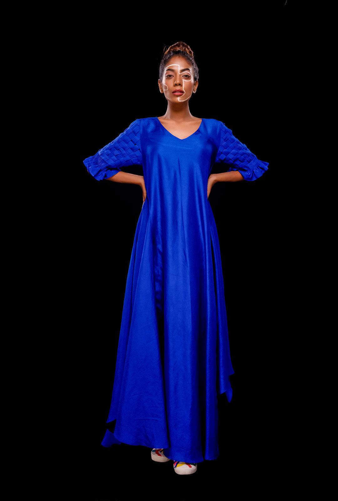 Front view of a blue asymmetrical gown with pintuck basket weave sleeve.