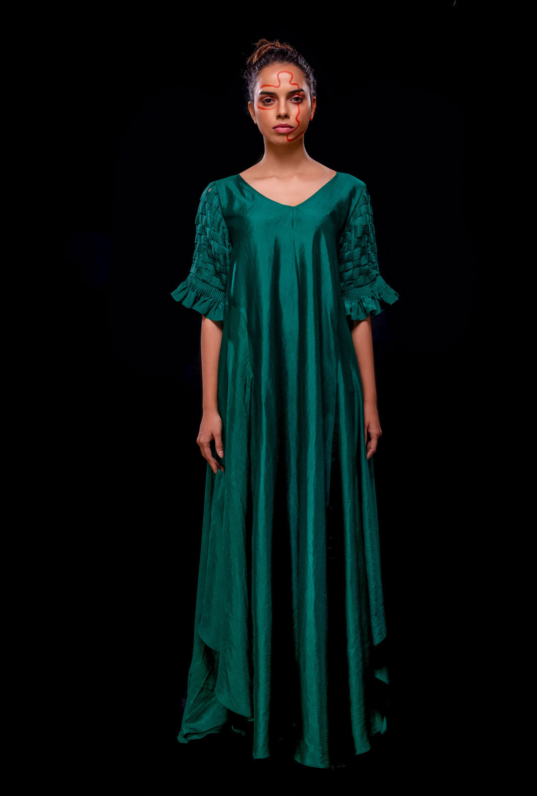 Front view of a green asymmetrical gown with pintuck basket weave sleeve.
