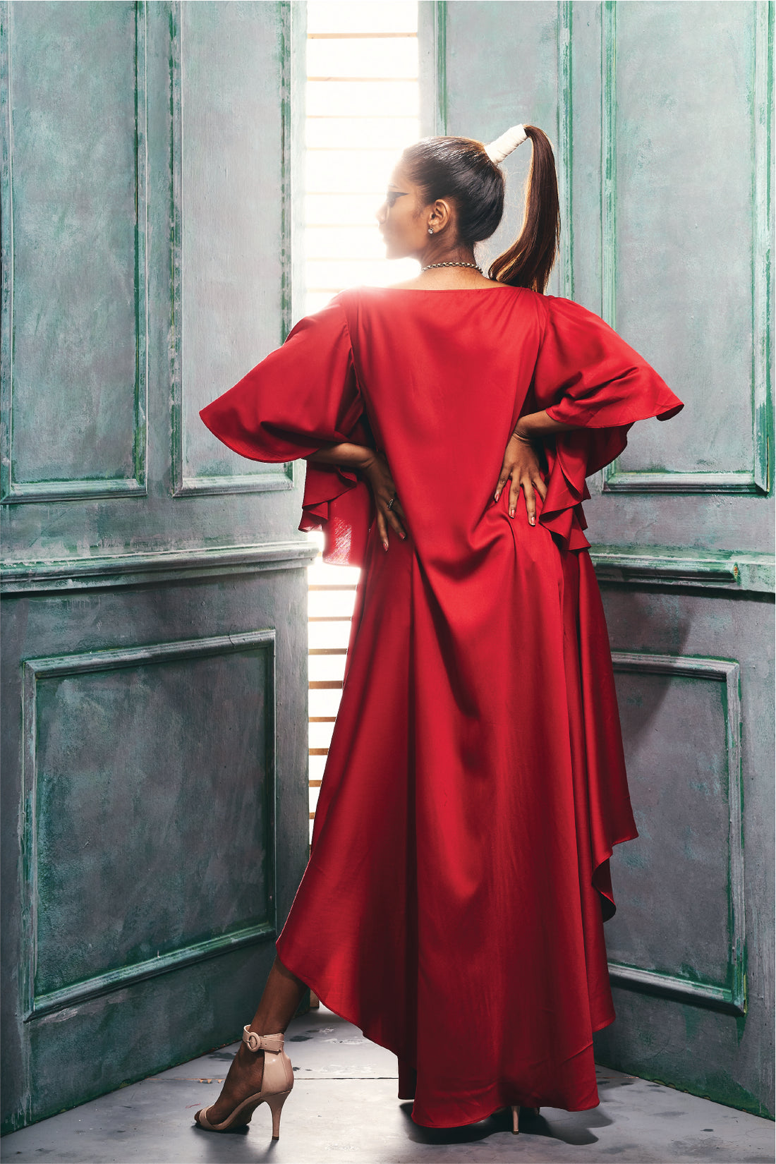 Side view of a maroon dress with asymmetrical hemline cascade sleeve.